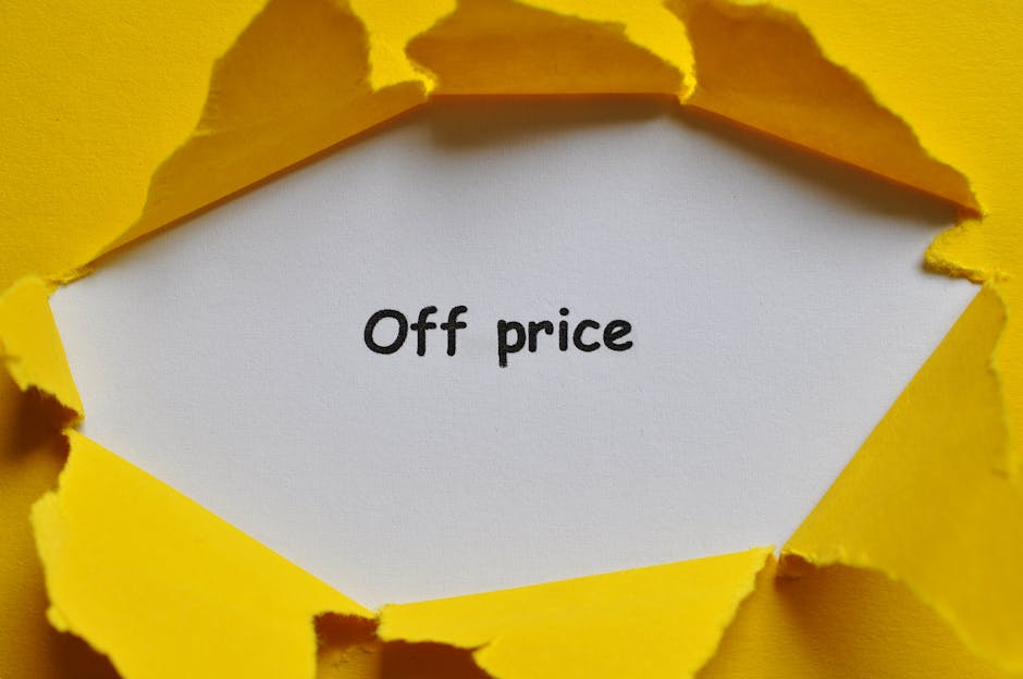 A close-up view of a bright yellow paper background with a tear revealing a white inner layer containing the text 'Discount Price' in black typewriter-style font. The torn edges of the yellow paper ar